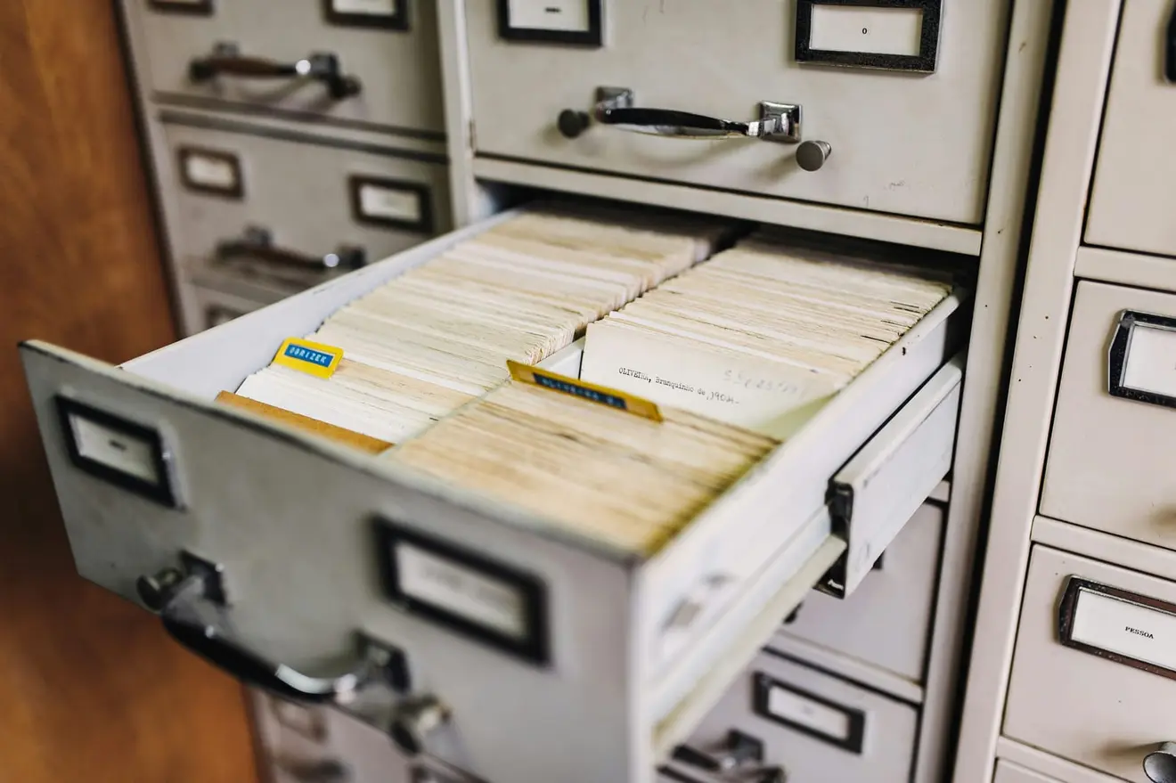 An open card-index drawer of Portuguese surname records, standing in for the taxpayer register a NIF entry sits in